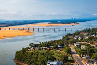Vista aérea de uma ponte atravessando um rio cercado por vegetação, em Boa Vista (RR).