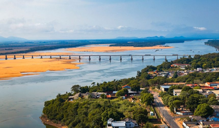 Vista aérea de uma ponte atravessando um rio cercado por vegetação, em Boa Vista (RR).