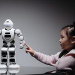 Menina interage com um brinquedo robótico em ambiente interno.