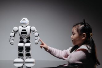 Menina interage com um brinquedo robótico em ambiente interno.